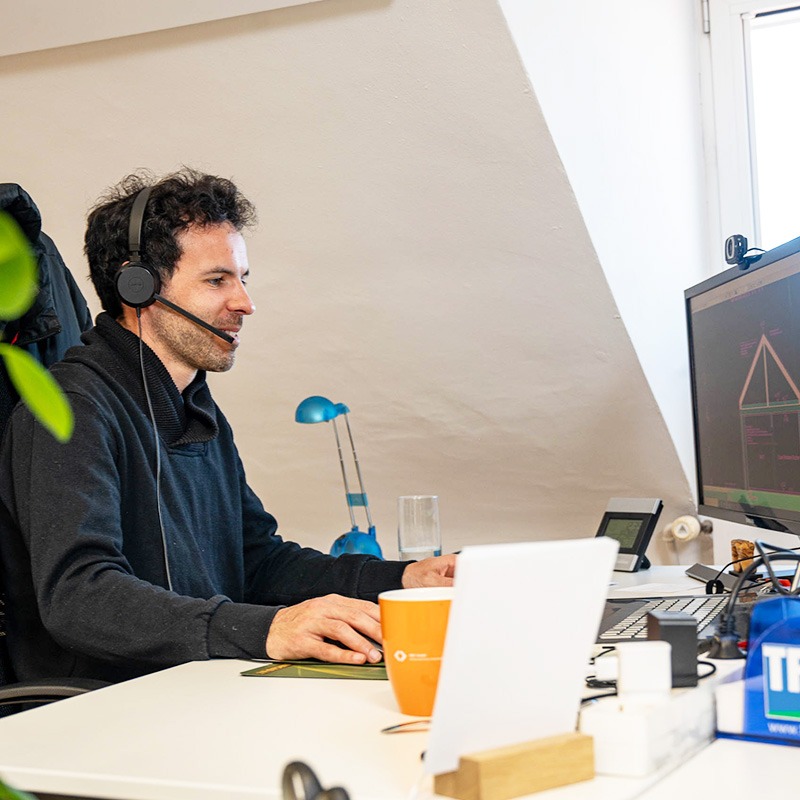 Ein junger Mann arbeitet an seinem Fixdesk-Schreibtisch im Coworking-Space.